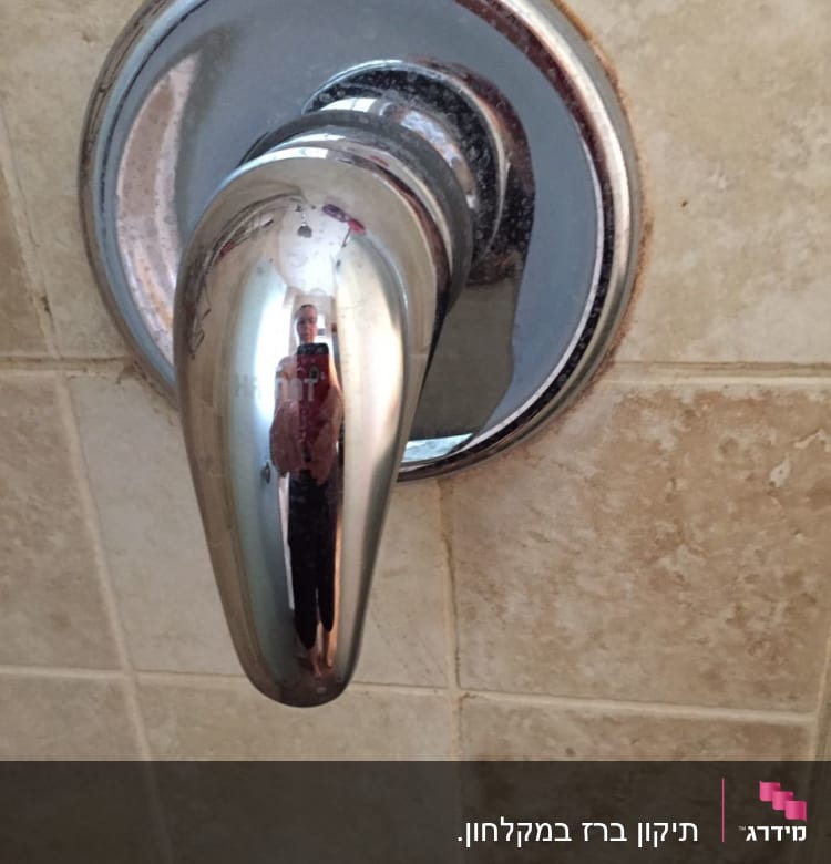 ידית ברז כרום על קיר אריחים